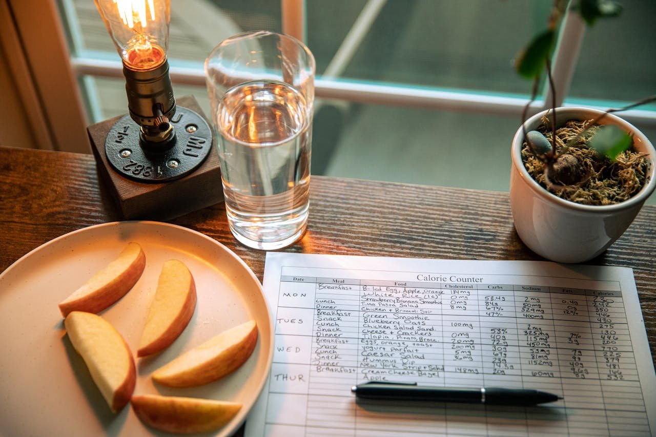 why-choose-us A cozy desk setup with apple slices, calorie counter, and water glass in warm lighting.