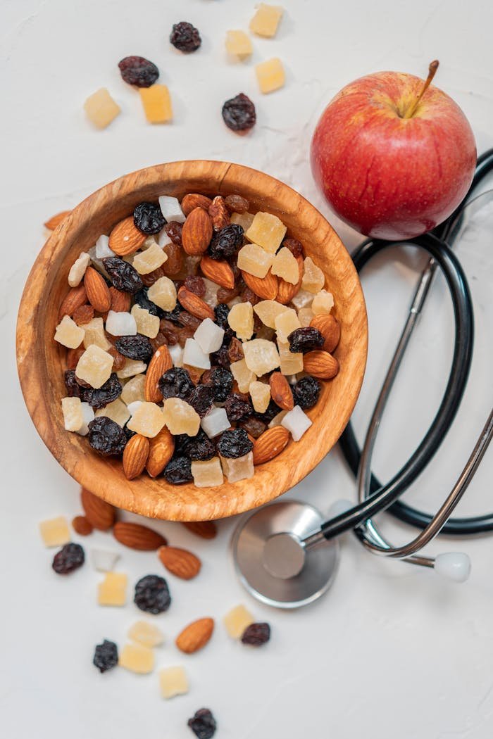 about-01 Top view of a healthy mix of nuts and dried fruits with an apple and stethoscope.